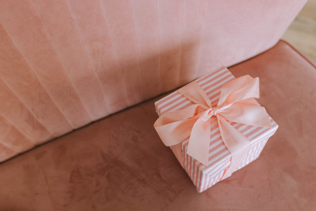 A pink and white striped gift box tied with a satin bow