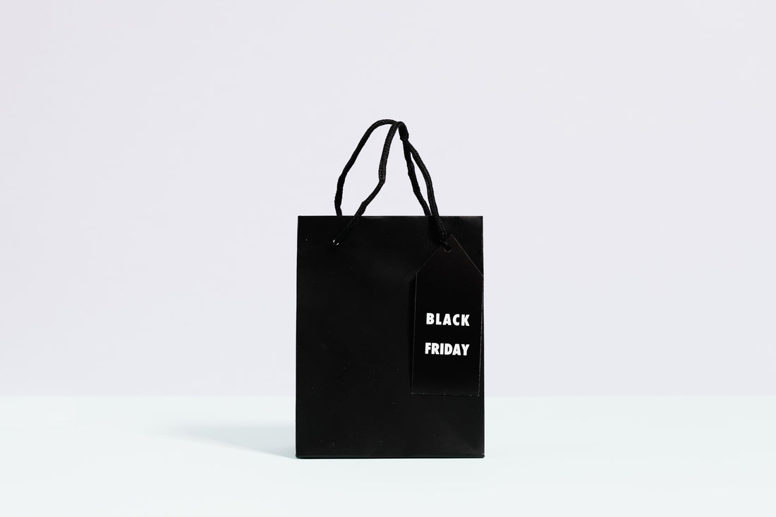 A black shopping bag with a Black Friday gift tag against a plain background