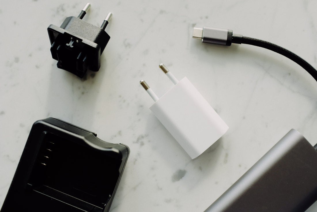 A Type-C charging cable, wall adapters, and a battery charger laid out on a marble surface