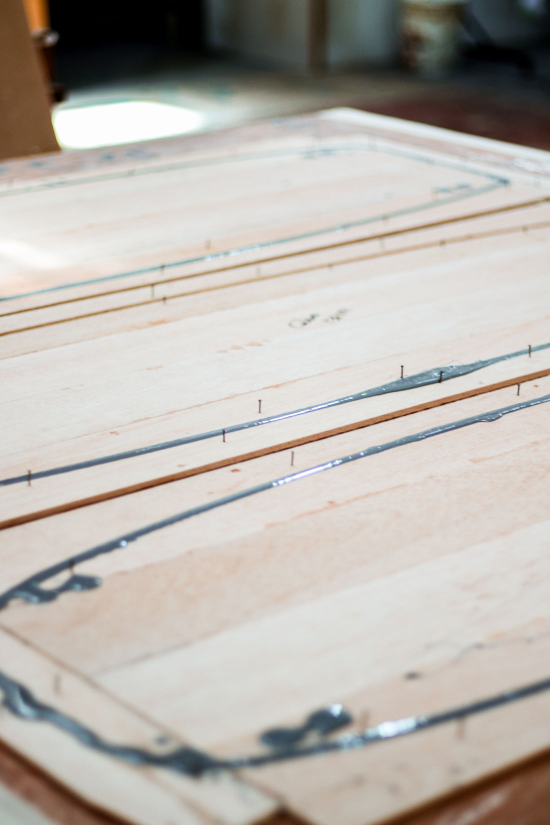 Thin lines of wood glue applied along the edges of laser-cut wooden panels