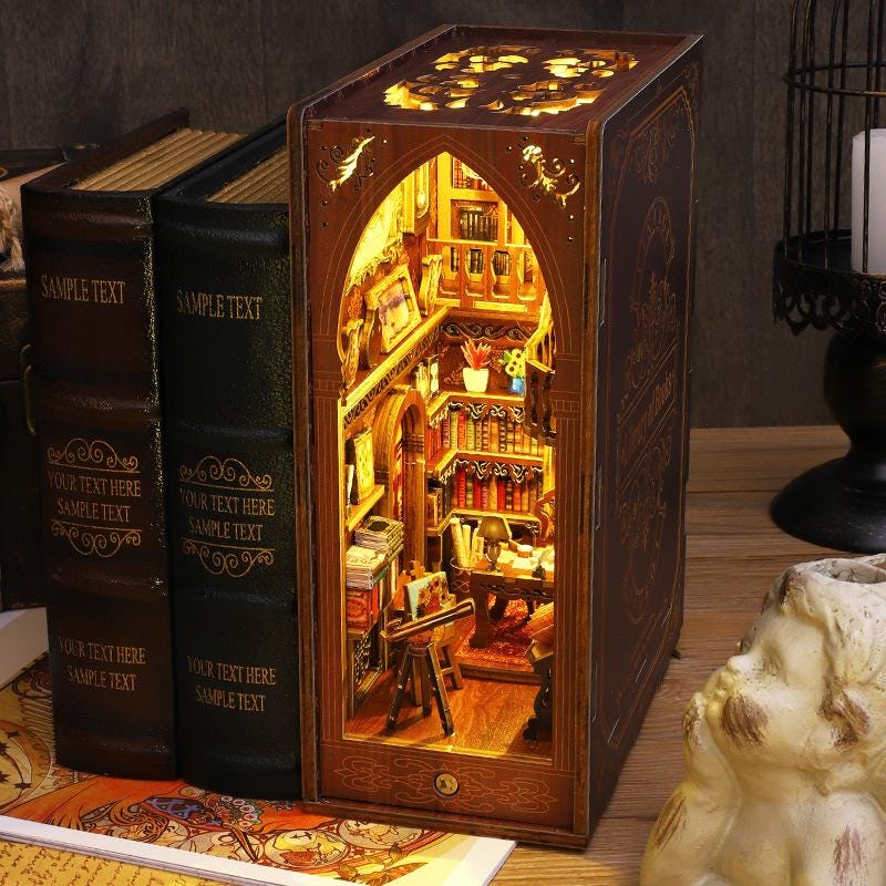 Finished wooden book nook glowing between two real books on a shelf