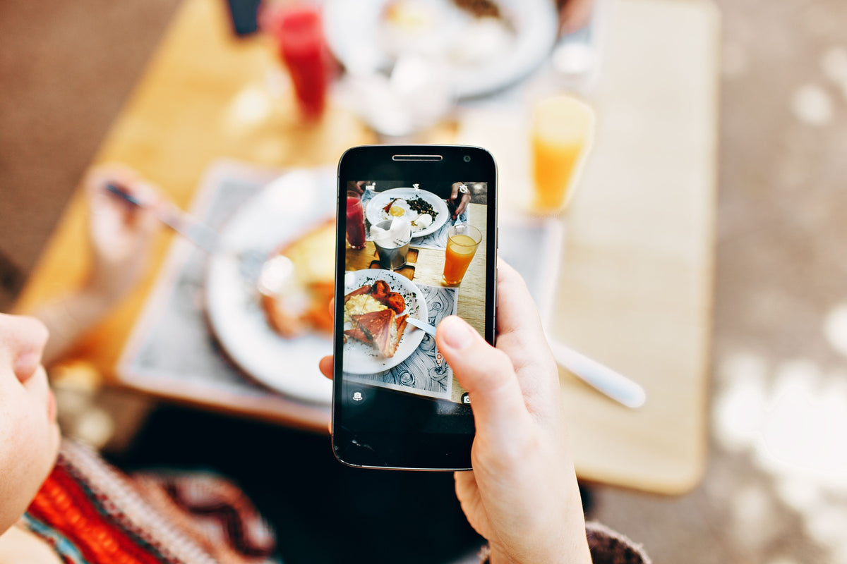 A person framing a close-up shot of a small tabletop scene with a smartphone