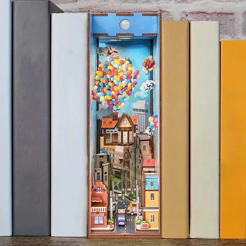 Floating Balloon House book nook standing between books on a bookshelf