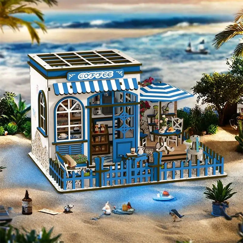 Santorini Sun Coffee dollhouse kit, whitewashed Mediterranean café with blue trim and striped awning, beach backdrop