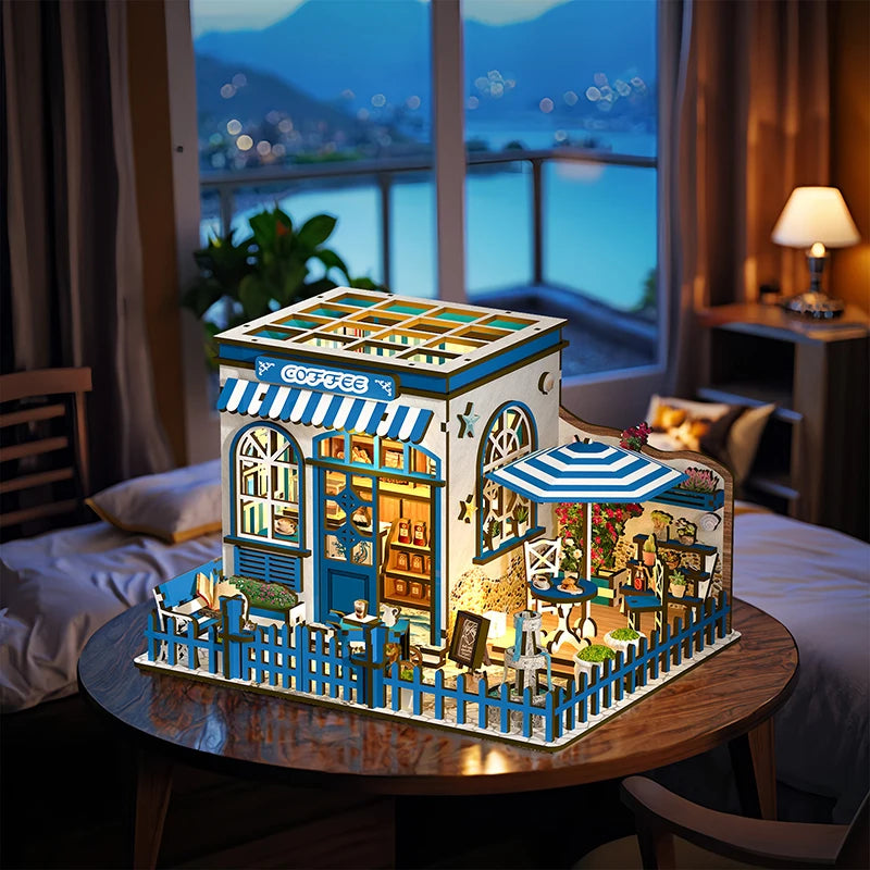 Santorini Sun Coffee miniature café lit up at night with warm LED lighting, seaside window view